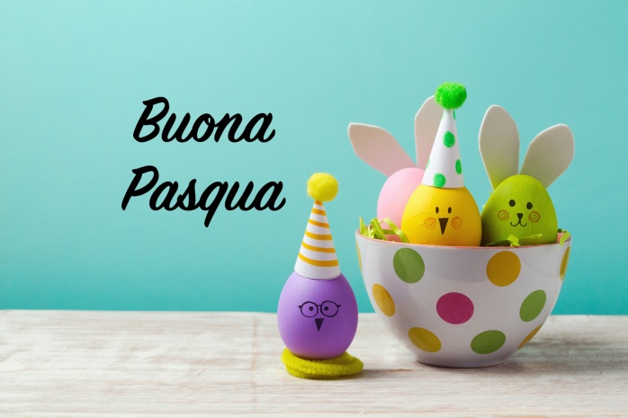 Easter holiday concept with cute handmade eggs, bunny, chicks and party hats in bowl on wooden table